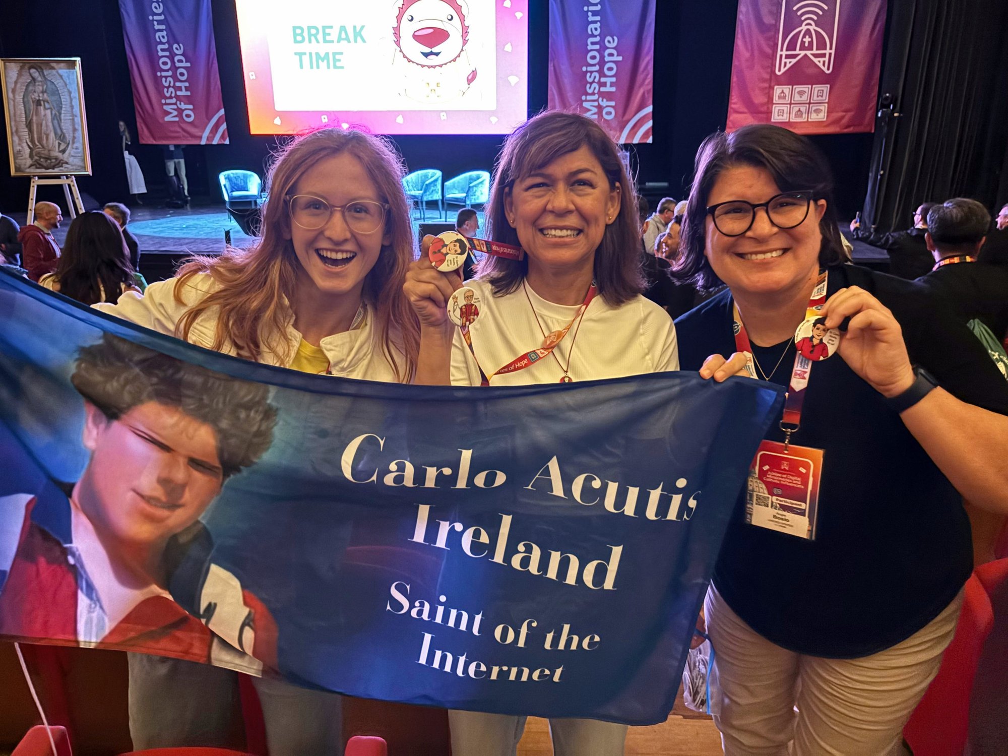Josefina Fernandez McEvoy, center, poses with Mary Aoife, left, from Ireland, and Angie Bosio, right, from Tennessee, while they hold a banner of soon-to-be-saint Carlo Acutis at the first Jubilee of Digital Missionaries and Catholic Influencers in Rome.