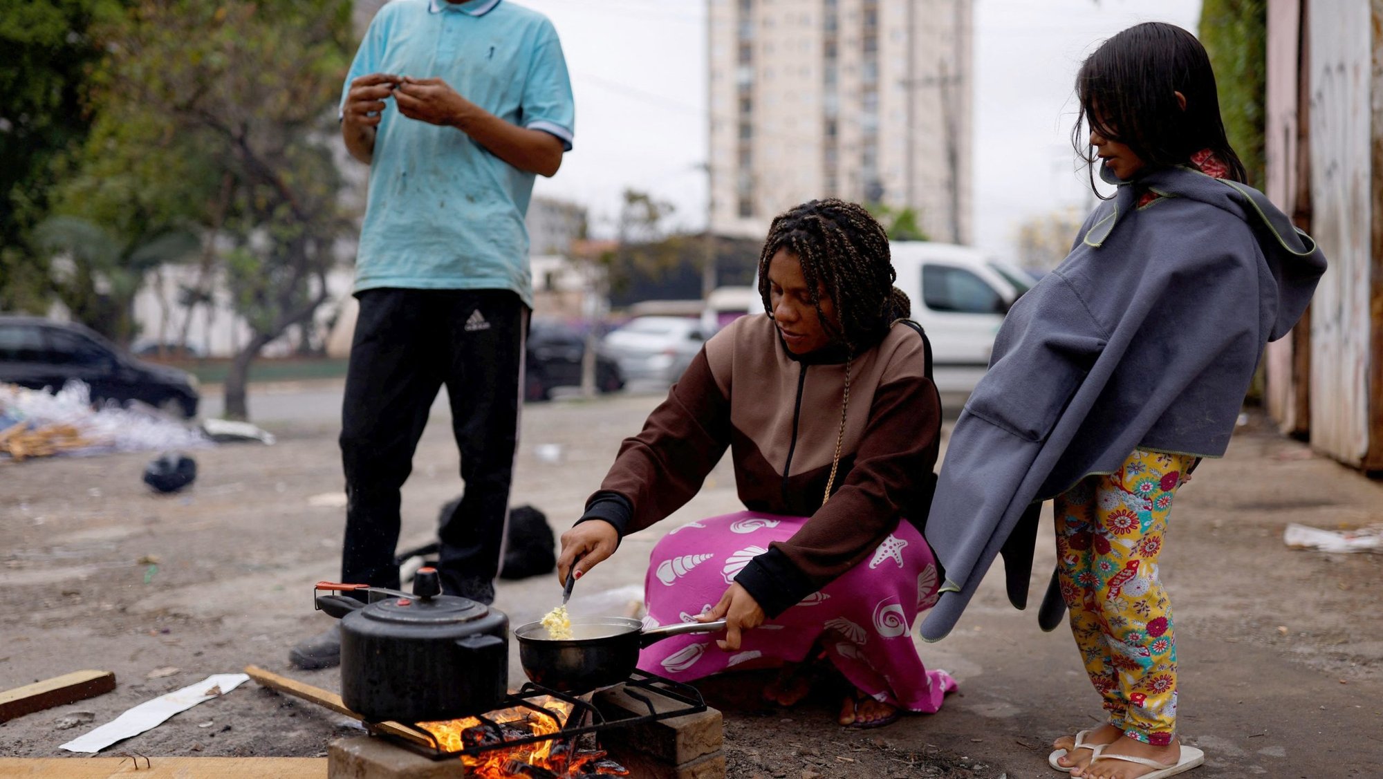 A woman burns wood on the street to cook a meal for her husband and their daughter outside their home in São Paulo in 2022. (OSV News/Amanda Perobelli, Reuters)