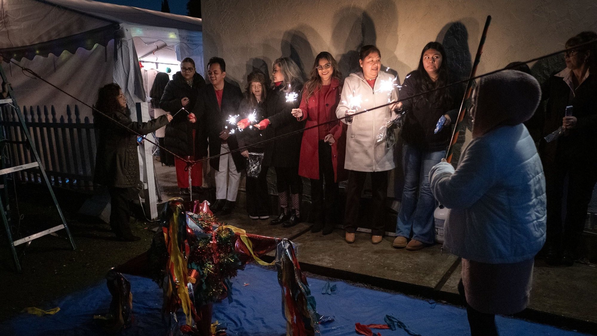 People watch as a young girl swings at a piñata with a stick during a traditional Christmas posada in San Jose, Calif., Dec. 21, 2024. The celebration, commonly called Las Posadas, is widely celebrated in the U.S., Mexico and other areas of Latin America to reenact Joseph and Mary's search for shelter on the eve of Christ's birth. The piñata used at this posada was a traditional seven-pointed piñata filled with candy, which represents the seven sins. After breaking the piñata and symbolically overcoming the seven sins, people are rewarded with the candies as they fall to the ground. (OSV News photo/David Maung)