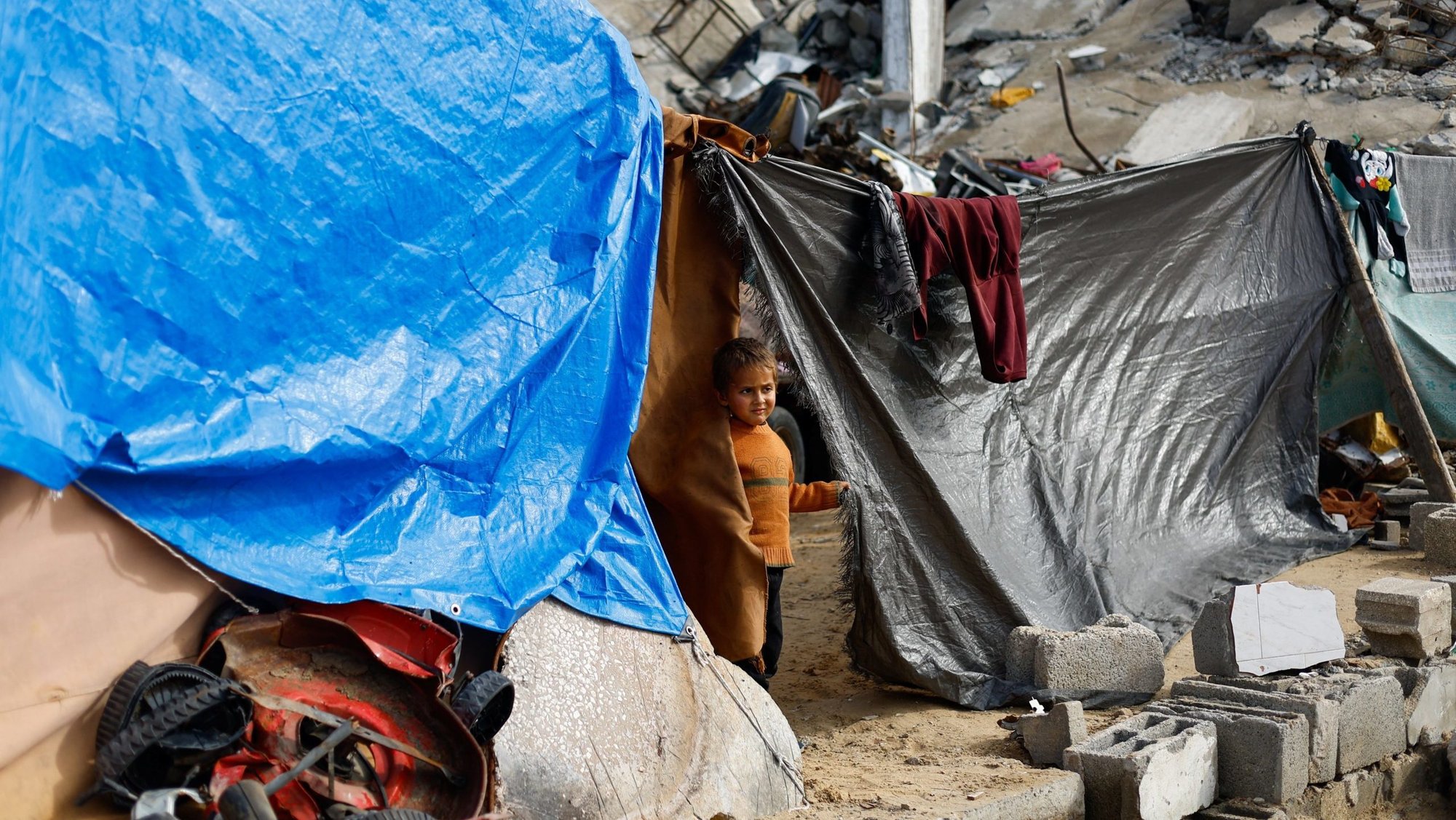A displaced Palestinian child looks on from a tent near the rubble of residential buildings destroyed during the war, on New Year's Eve in Jabalia, northern Gaza Strip, Dec. 31, 2025. Israel on Dec. 30 said it had suspended operations of more than two dozen humanitarian organizations, including, including Caritas. (OSV News photo/Mahmoud Issa, Reuters)