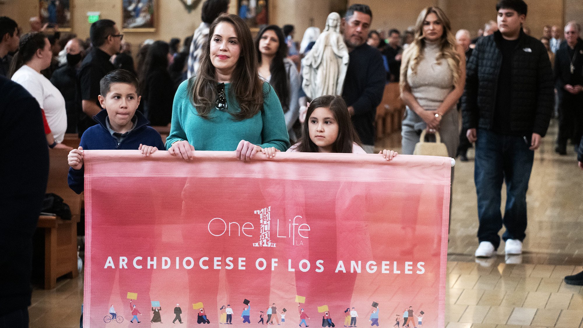 The Gonzalez and Magallon families, who both lost their homes in the Eaton Fire, process into the Cathedral of Our Lady of the Angels to begin the OneLife LA event on Jan. 18, 2025. (Victor Alemán)