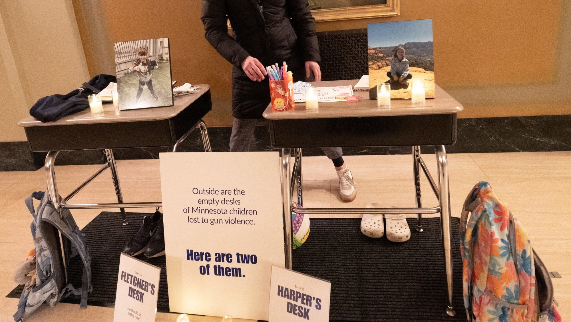 Jackie Flavin, mother of Harper Moyski, who died in the Aug. 27, 2025, shooting at Annunciation church in south Minneapolis, looks at desks she set up Feb. 23, 2026, in honor of Harper and another Annunciation student, Fletcher Merkel, who also died in the shooting. Flavin and other Annunciation volunteers set up those two desks plus others outside to signify children who have died by gun violence in Minnesota since 2021. They are part of an organization of parents called Annunciation Light Alliance, which is lobbying to protect children from gun violence. (OSV News photo/Dave Hrbacek, The Catholic Spirit)