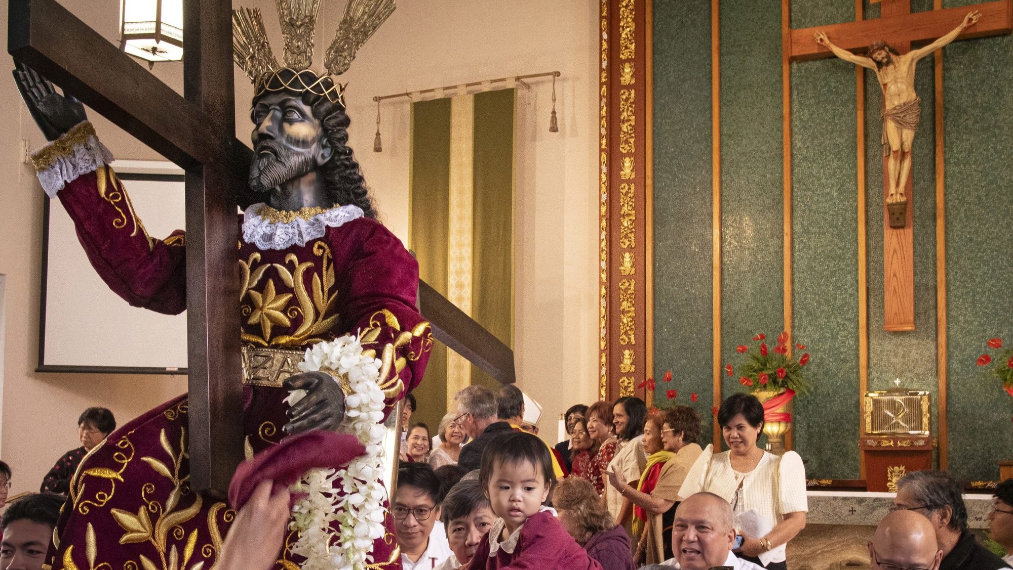 Tharese Carpio, center, is raised for a blessing to the new statue of the Black Nazarene at Holy Family Church in Artesia Feb. 14. (Juanito Holandez Jr.)