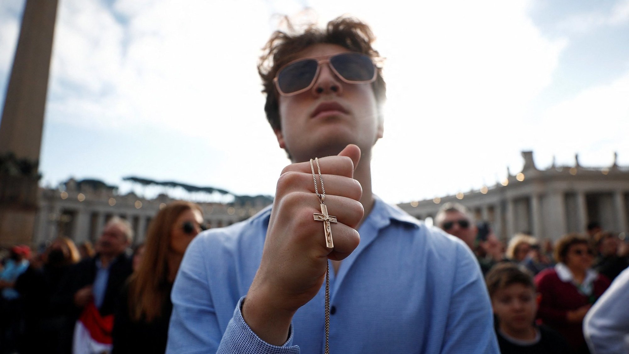 A man holds a chain with a crucifix as Pope Francis prays the Angelus at the Vatican on the World Day of Peace Jan. 1, 2023. (OSV News photo/Guglielmo Mangiapane, Reuters)