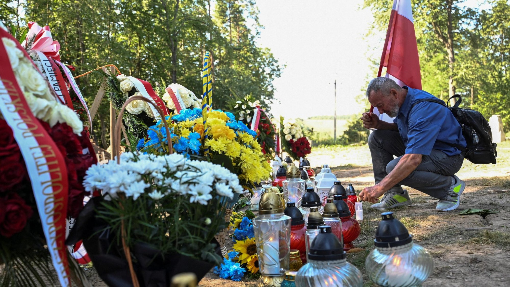 A man holding a Polish national flag with coat of arms lights a candle at the site of a mass burial ceremony of Poles killed by Ukrainian nationalists during World War II in the former Polish village of Puznyky, in Ukraine's Ternopil region Sept. 6, 2025. In 2024, Ukraine granted Poland access to the sites in the western part of the country, once part of Poland, to carry out joint search and exhumation of the remains of Polish victims. (OSV News/Anastasiia Smolienko, Reuters)