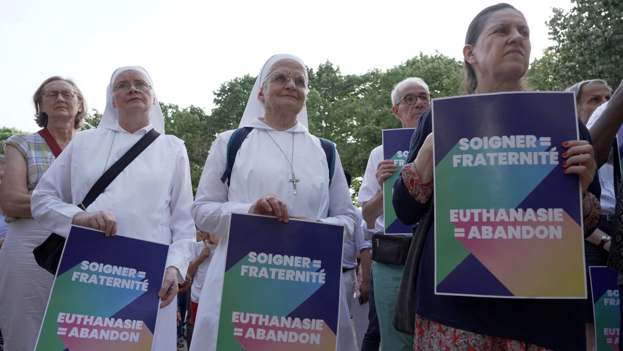 Opponents of "assisted dying" gather during a vote by members of parliament on a bill establishing the right to medical aid in dying at the National Assembly in Paris July 15, 2026. The placards read "Caring = fraternity – Euthanasia = abandonment. In reaction the same day, the French bishops decried the vote as 'turning point' in nation's history of alleviating suffering and accompanying "each person to the natural end of their life." (OSV News photo/Noemie Olive, Reuters)