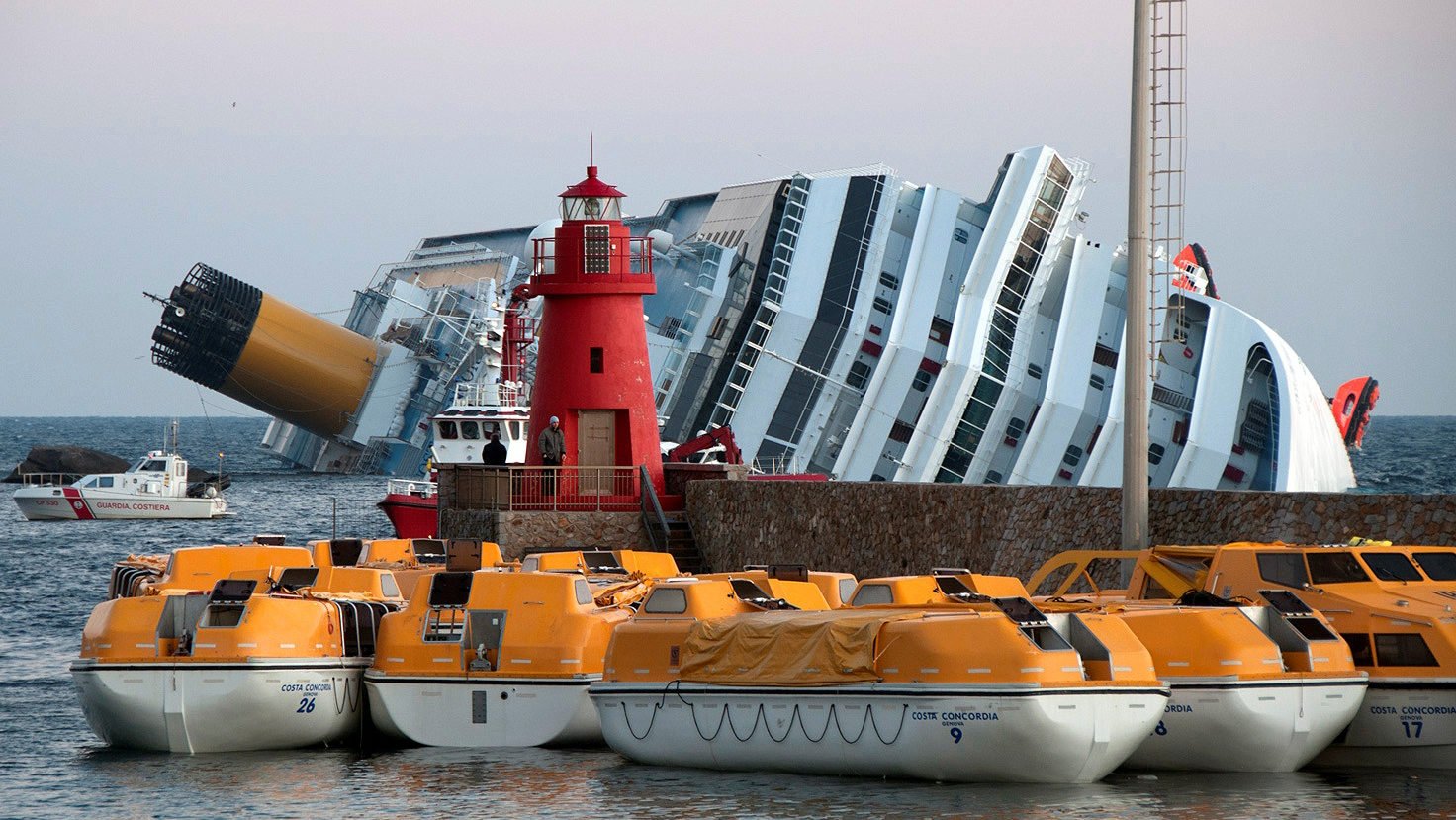 The partially capsized Costa Concordia and multiple life boats at shore. (Rvongher/CC BY-SA 3.0 via Wikimedia Commons)