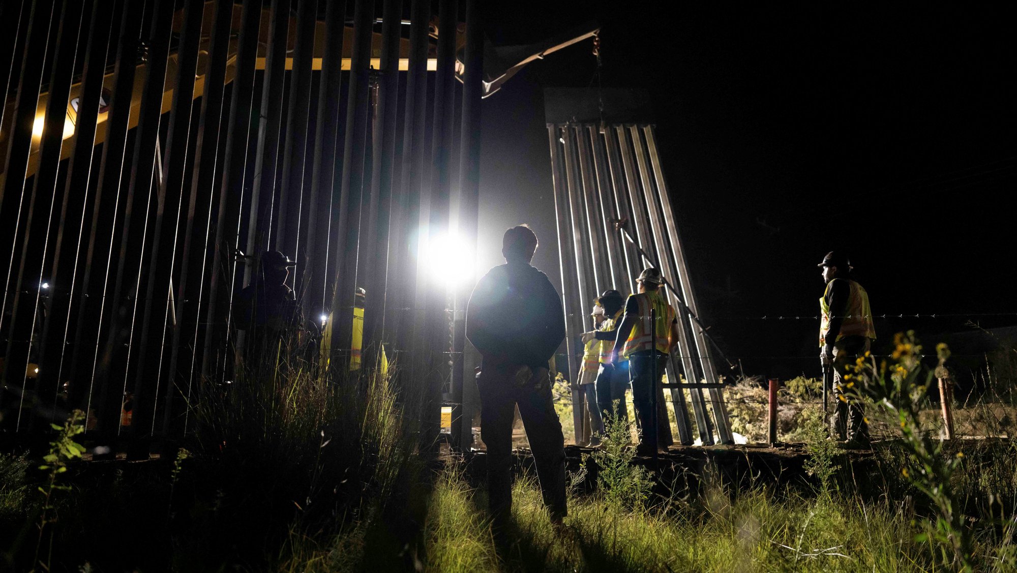 A lone protester looks on as Fisher Sand & Gravel construction crews build the US-Mexico border fence in Lochiel, Ariz., Oct. 8, 2026. (OSV News photo/Rebecca Noble, Reuters)