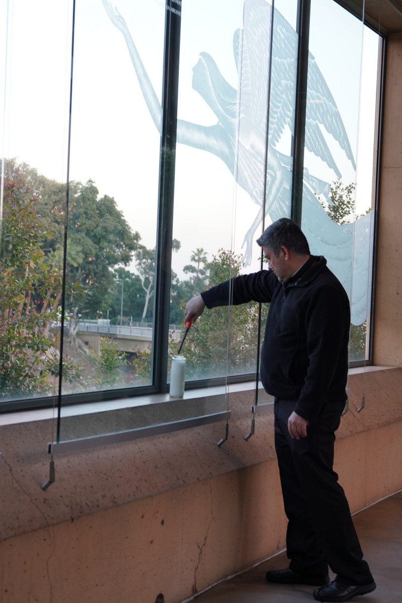 Fr. Paúl Velasquez lights a candle in support of medical workers and their families along the edge of the Cathedral of Our Lady of the Angels plaza overlooking the 101 freeway in downtown Los Angeles. (Sarah Yaklic)