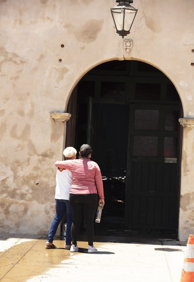 Los feligreses de la Misión de San Gabriel lloran afuera de la puerta de la iglesia dañada el 11 de julio. (Víctor Alemán)