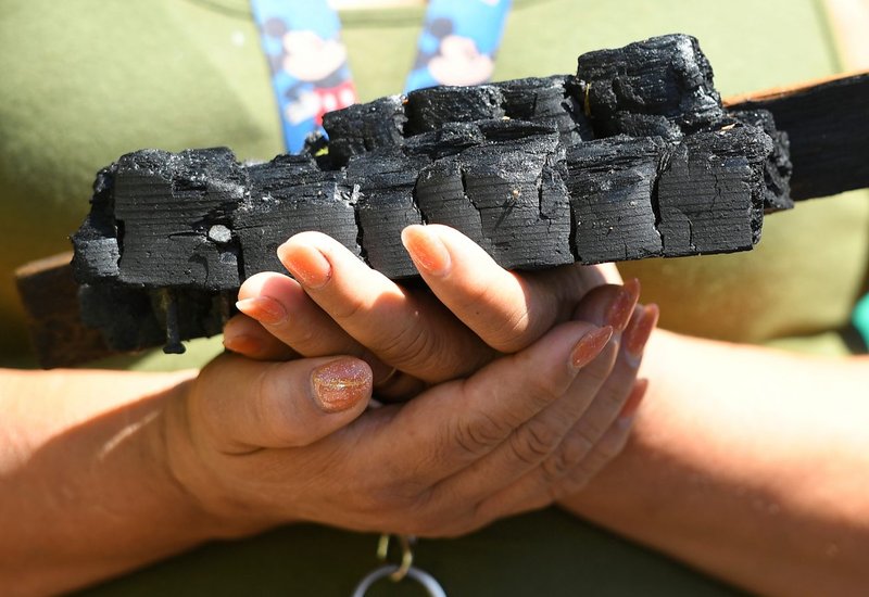 Un feligres sostiene madera carbonizada de la Misión de San Gabriel, dañada por el fuego. (Fotografía de John McCoy)