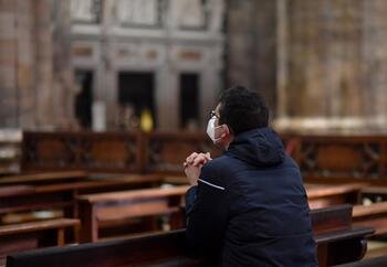 Un hombre con una máscara protectora reza dentro de la famosa catedral de Milán el 11 de febrero de 2021, después de su reapertura al público luego de que se relajaran las restricciones del COVID-19. (Foto CNS/Daniele Mascolo, Reuters)