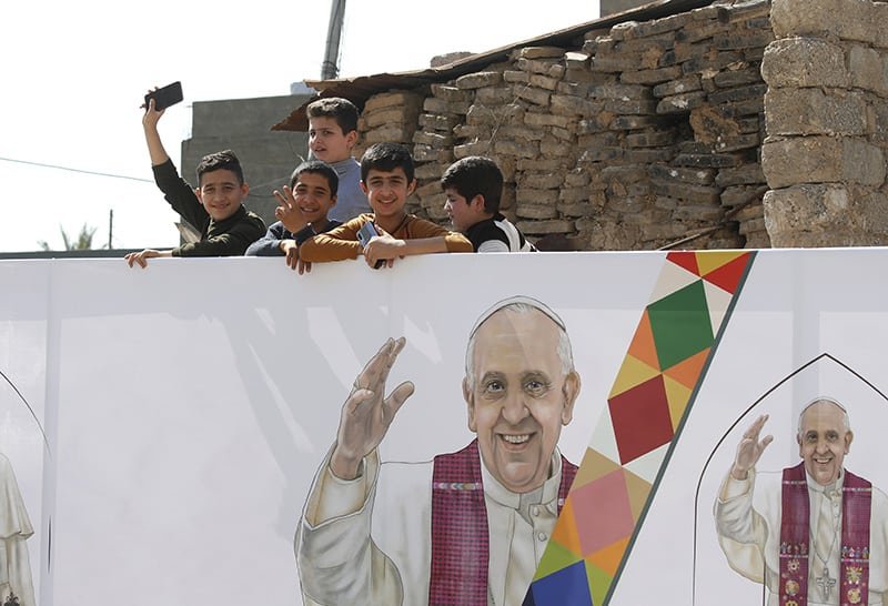 Niños son vistos cerca de una imagen del Papa Francisco durante la visita del Papa con la comunidad en la Iglesia de la Inmaculada Concepción en Qaraqosh, Irak, el 7 de marzo de 2021. Foto del CNS/Paul Haring