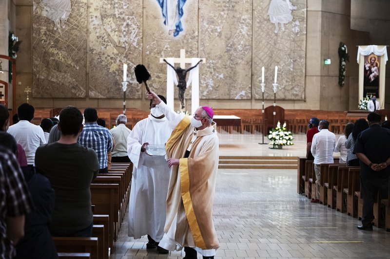 Monseñor Gómez bendice a la congregación aspersando agua bendita durante la Vigilia Pascual en la noche del Sábado Santo. (Víctor Alemán)