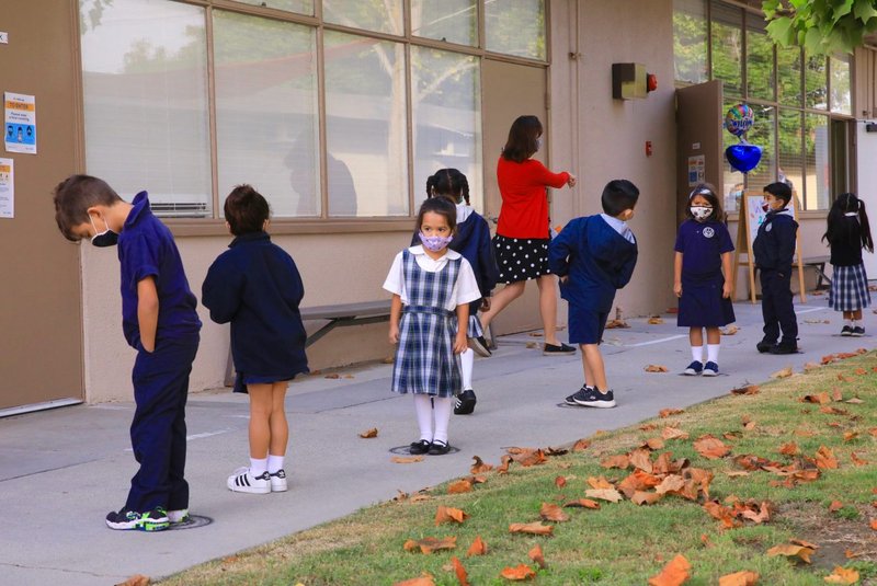 Los estudiantes de escuelas católicas en Long Beach hacen fila en marcadores de distancia en la escuela en octubre de 2020. (David Amador Rivera)