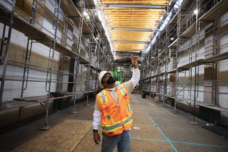 Un trabajador de la construcción mira los andamios que rodean el interior de la Misión San Gabriel. (Víctor Alemán)