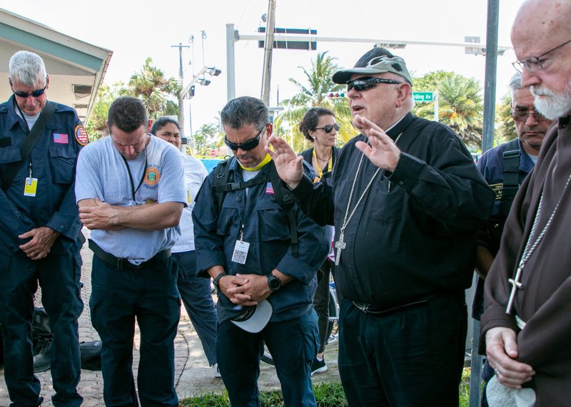 El arzobispo Thomas G. Wenski de Miami bendice al personal de búsqueda y rescate en Surfside, Florida, el 2 de julio de 2021, después de llegar al sitio del colapso de la torre Champlain Towers sur con el cardenal Sean P. O'Malley de Boston. El arzobispo y el cardenal rezaron y bendijeron el sitio mientras también visitaban, rezaban y bendecían a los equipos de búsqueda y rescate que han estado trabajando 24 horas al día, 7 días a la semana desde el colapso. (Foto CNS/Ana Rodriguez-Soto, Florida Catholic)