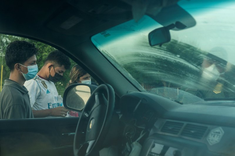 Migrantes de Centroamérica en Peñitas, Texas, aparecen en esta foto junto a un automóvil mientras son procesados por un agente de la Patrulla Fronteriza de EE.UU. después de cruzar el Río Bravo el 8 de julio de 2021. (Foto CNS/Go Nakamura, Reuters)