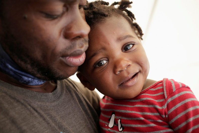 Un migrante haitiano y un niño que buscan refugio en los Estados Unidos se encuentran afuera de un albergue, en Monterrey, México, el 28 de septiembre de 2021. (Foto de CNS / Daniel Becerril, Reuters)