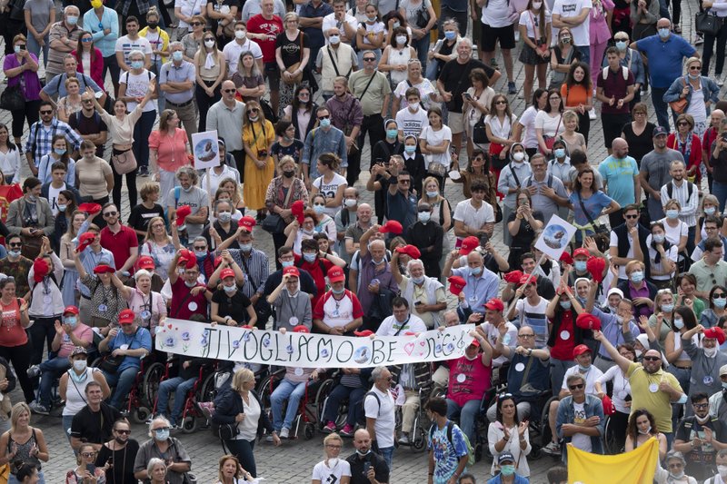 Un grupo de personas en la Plaza de San Pedro asiste al Ángelus rezado por el papa Francisco desde la ventana de su estudio en el Vaticano el 4 de octubre de 2021. La pancarta en italiano dice "Te amamos." (Foto CNS/Vatican Media)