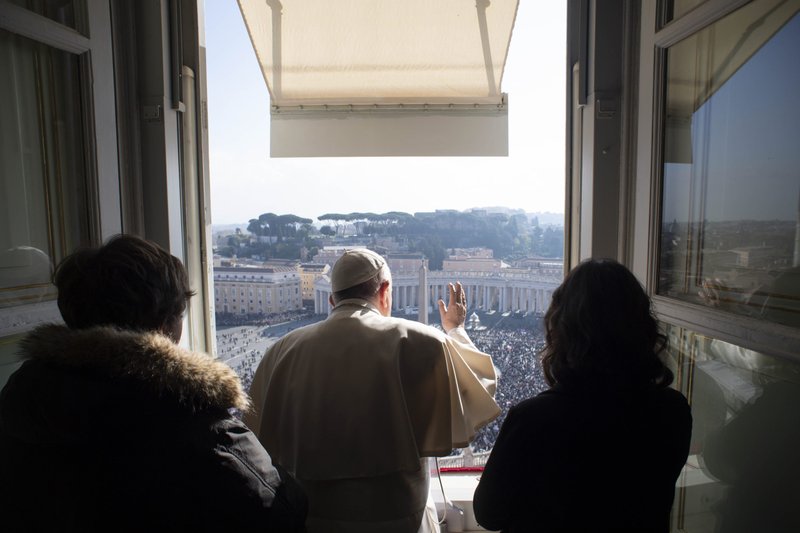 El papa Francisco, acompañado por dos jóvenes de la Diócesis de Roma, dirige el Ángelus desde la ventana de su estudio con vista a la Plaza de San Pedro en el Vaticano el 21 de noviembre de 2021. (Foto CNS/Vatican Media)