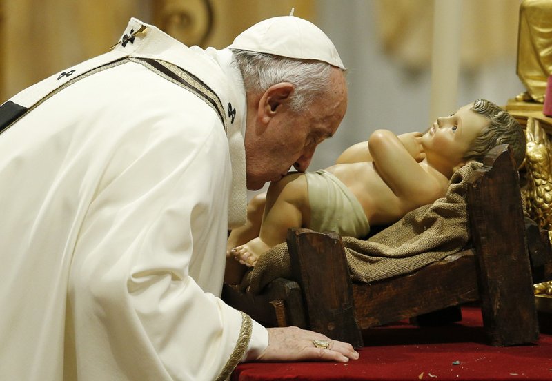 El Papa Francisco besa una estatuilla del niño Jesús al inicio de la misa de Nochebuena en la Basílica de San Pedro en el Vaticano el 24 de diciembre de 2021. (Foto CNS /Paul Haring)