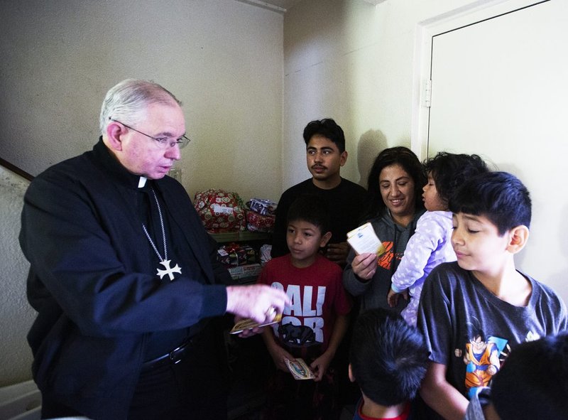 Monseñor Gómez entrega los regalos a uno de los beneficiarios de Adopta una Familia en 2019. (Víctor Alemán)
