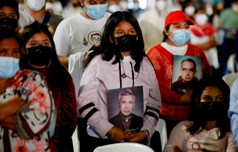 Feligreses portan las imágenes de los nuevos beatos, el jesuita mártir, Rutilio Grande y el mártir franciscano Cosme Spessotto, durante la misa de beatificación en San Salvador, El Salvador, el 22 de enero de 2022. (Foto CNS/José Cabezas, Reuters)