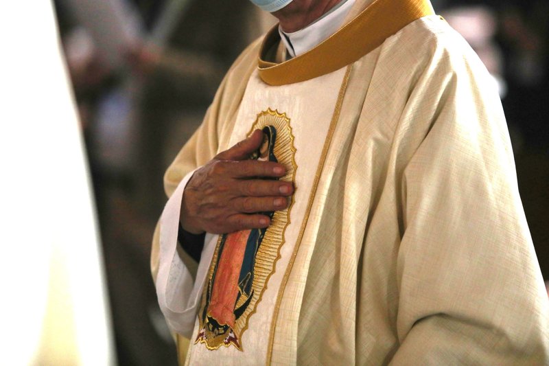 Un clérigo toca una imagen de Nuestra Señora de Guadalupe en sus vestiduras durante una misan en Basílica de Nuestra Señora de Guadalupe en la Ciudad de México el 21 de noviembre de 2021. (Foto CNS /Emilio Espejel)