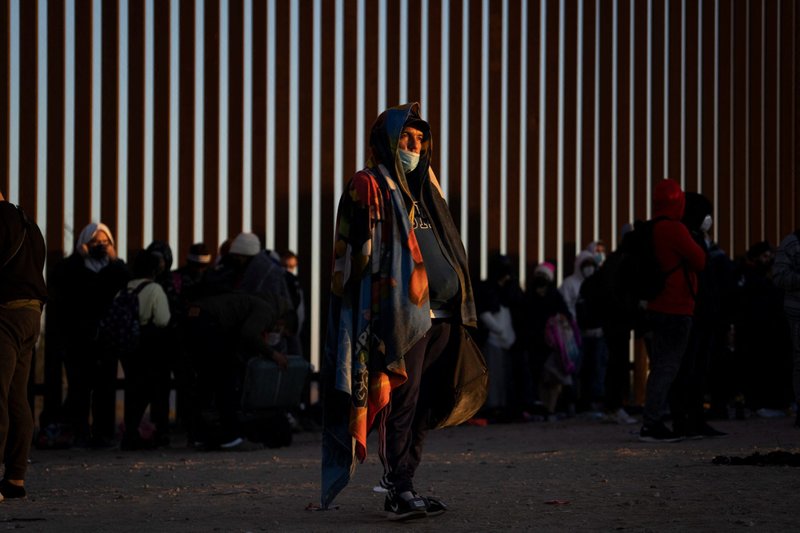 Migrantes que buscan asilo en Yuma, Arizona, el 23 de enero de 2022, paran cerca del muro fronterizo mientras esperan ser procesados por la Patrulla Fronteriza de EE. UU. (Foto CNS/Go Nakamura, Reuters)