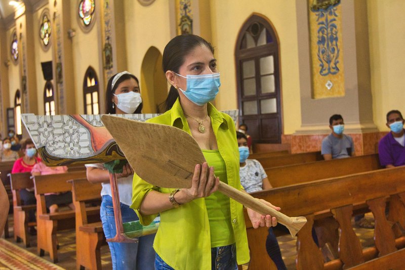 Omaira Pérez Lazo lleva el remo de una canoa, símbolo de la estrecha vinculación de los pueblos amazónicos con los ríos de la región, parte del ofertorio en una misa el 13 de febrero de 2022, en Iquitos, Perú, donde se ofrecieron oraciones por las personas que sufren derrames de petróleo en la Amazonía y en la costa peruana. (Foto CNS/Barbara Fraser)