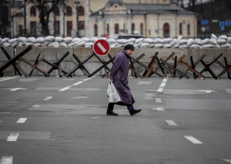 Una mujer cruza la calle mientras se ven construcciones antitanques en Kyiv, Ucrania, el 7 de marzo de 2022. (Foto CNS/Gleb Garanich, Reuters)