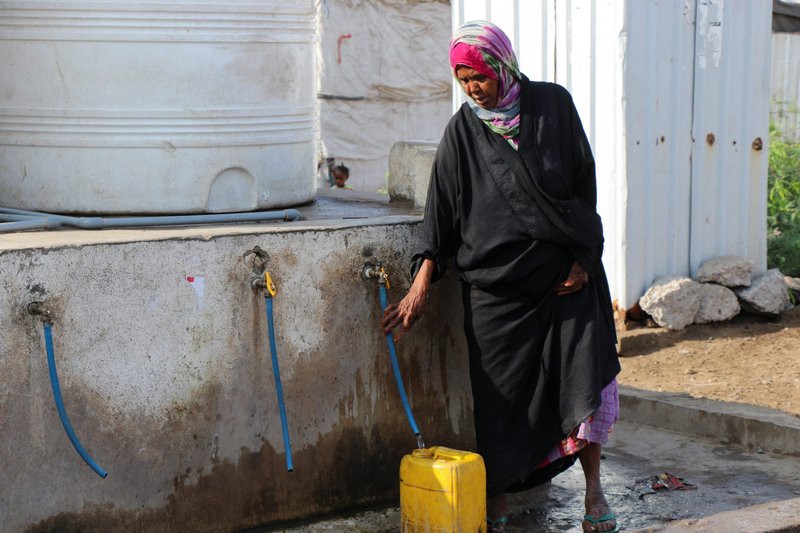 Una mujer llena un contenedor con agua en un campamento improvisado para desplazados internos en Adén, Yemen, el 15 de marzo de 2022. El papa Francisco dijo que las verdaderas batallas que la gente debería pelear son contra el hambre, la sed, las enfermedades, la pobreza y la esclavitud. (Foto CNS/Fawaz Salman, Reuters)
