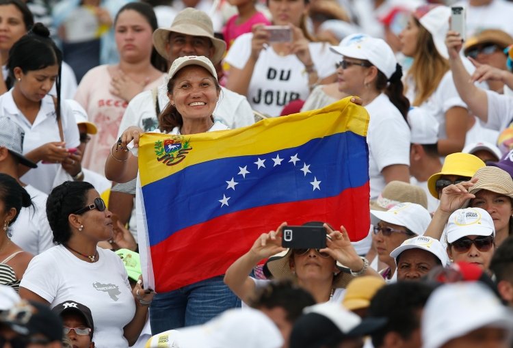 Una mujer sostiene una bandera antes de que el Papa Francisco celebre la misa en la terminal de Contecar en Cartagena, Colombia, el 10 de septiembre de 2017. (Foto Paul Haring/CNS.)