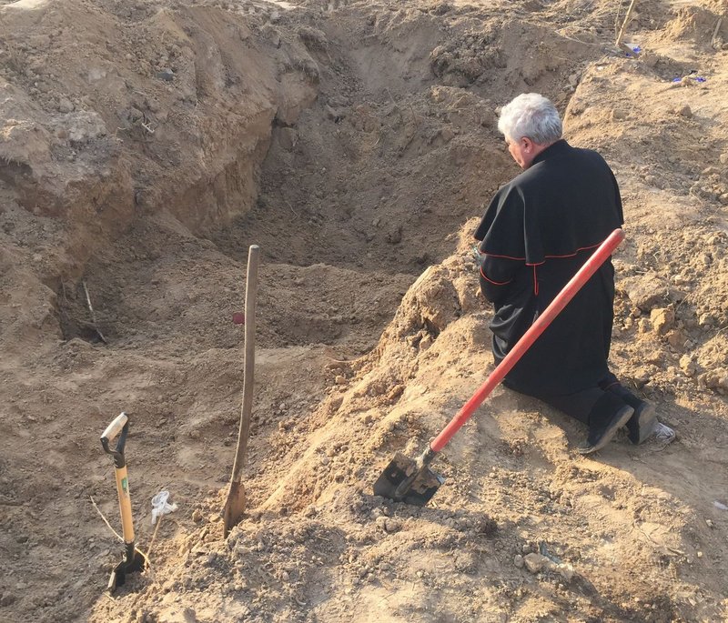 El cardenal Konrad Krajewski, limosnero papal, que se encuentra en Ucrania como enviado papal, reza sobre una fosa común cerca de Borodyanka, Ucrania, el 15 de abril de 2022. (Foto CNS /Vatican Media)