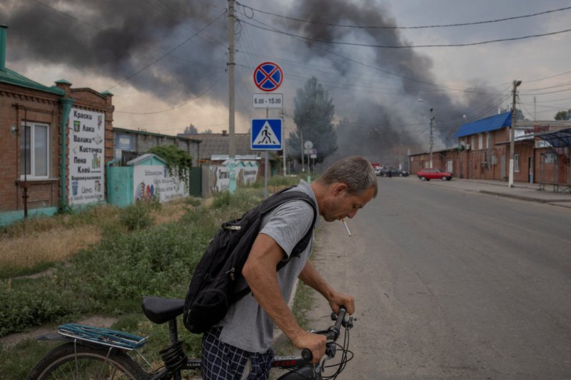 Un hombre en Sloviansk, Ucrania, empuja una bicicleta a través de una calle frente al mercado después del bombardeo de Rusia el 5 de julio de 2022. (Foto CNS /Marko Djurica, Reuters)