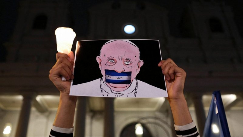 Un nicaragüense exiliado en Costa Rica sostiene un dibujo del Papa Francisco con una bandera nicaragüense cubriendo su boca durante la "Vigilia de la Fe y la Libertad" fuera de la Catedral Metropolitana en San José, Costa Rica, el 19 de agosto de 2022. (Foto CNS /Mayela Lopez, Reuters)