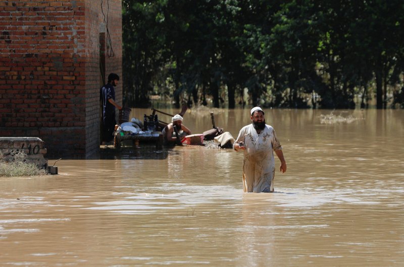 Un hombre vadea las aguas de la inundación, tratando de salvar sus pertenencias, luego de las fuertes lluvias durante la temporada del monzón en Charsadda, Pakistán, el 28 de agosto de 2022. (CNS photo/Fayaz Aziz, Reuters)