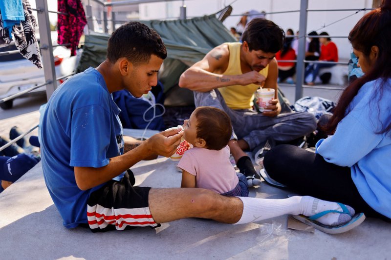 Migrantes venezolanos, expulsados de EE. UU., comen en la frontera entre EE. UU. y México en Ciudad Juárez, México, el 16 de octubre de 2022. Fueron expulsados a México bajo el Título 42 como parte de una nueva política para reducir la cantidad de cruces ilegales. (Foto CNS/José Luis González, Reuters)