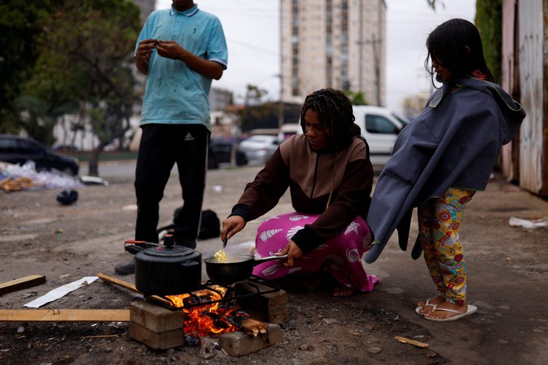 Carla Márquez, de 36 años, con seis meses de embarazo, quema leña en la calle para cocinar para su esposo, Carlos Henrique Mendes, de 25 años, y su hija, Gabriela, de 5, afuera de su casa en São Paulo el 16 de septiembre de 2022. Márquez y su familia viven en una habitación pagada por una iglesia y luchan por alimentar a su hija. Entre los desafíos identificados durante el proceso de la Primera Asamblea Eclesial de la iglesia latinoamericana se encuentran las desigualdades sociales y económicas agudizadas por la pandemia. (Foto CNS/Amanda Perobelli, Reuters)