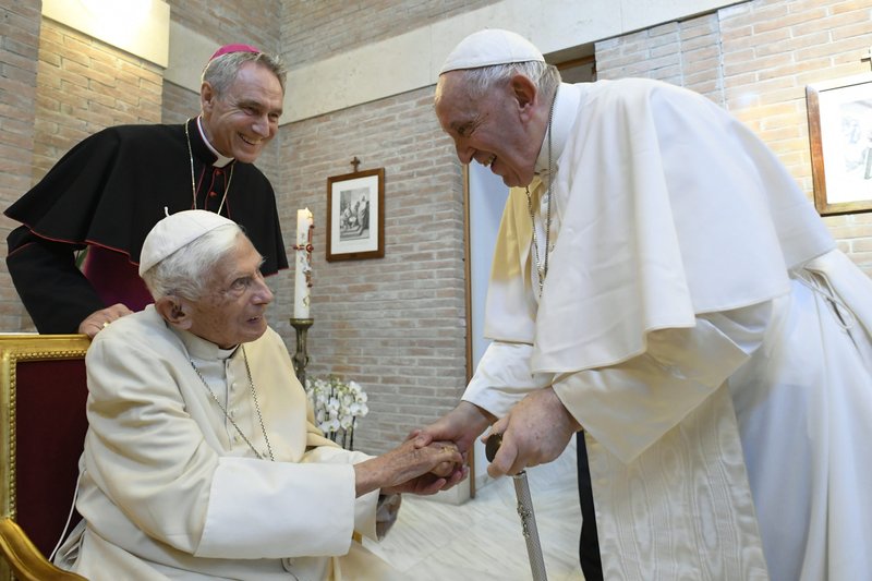 El Papa Francisco saluda al Papa retirado Benedicto XVI en el monasterio Mater Ecclesiae después de un consistorio para la creación de 20 nuevos cardenales en la Basílica de San Pedro en el Vaticano el 27 de agosto de 2022. El arzobispo Georg Gänswein, secretario privado del Papa, le observa. (CNS /Vatican Media)