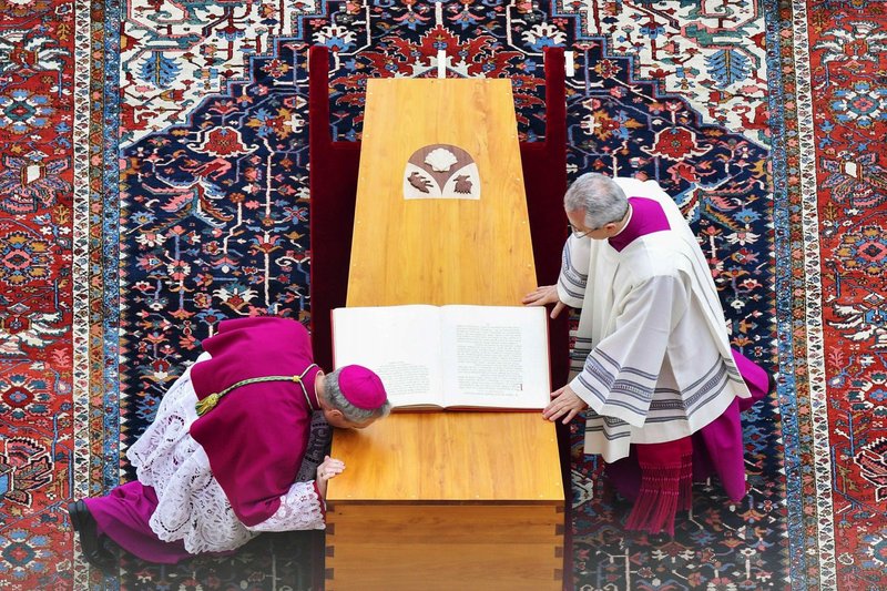 El arzobispo Georg Gänswein, secretario privado del papa Benedicto XVI, besa el féretro del difunto papa durante su misa funeral en la plaza de San Pedro del Vaticano el 5 de enero de 2023. En la foto también aparece monseñor Diego Giovanni Ravelli, maestro de ceremonias litúrgicas del Papa Francisco. (CNS/Vatican Media)