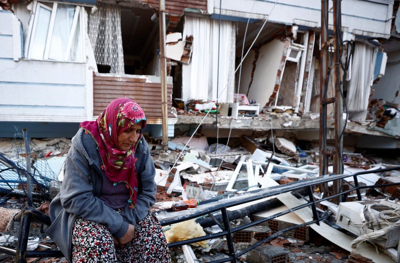 An earthquake survivor sits amid the rubble of destroyed homes in Hatay, Turkey, Feb.7, 2023. A powerful 7.8 magnitude earthquake rocked areas of Turkey and Syria early Feb. 6, toppling hundreds of buildings and killing thousands. (OSV News photo/Guglielmo Mangiapane, Reuters)