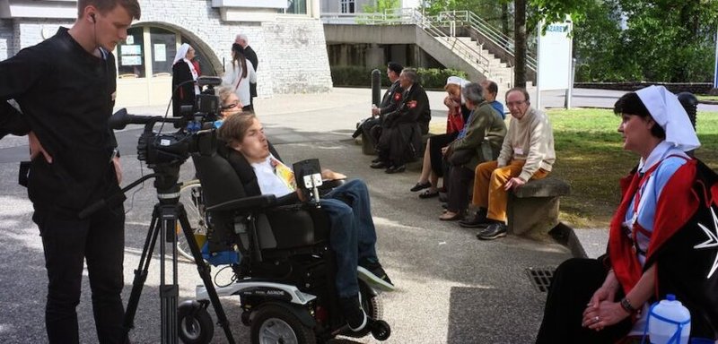 Kamil Cierniak vivió 26 años con atrofia muscular espinal (AME), una enfermedad terminal. A pesar de la enfermedad, estudió en múltiples facultades de las universidades de Cracovia (Polonia). En 2015, Kamil recibió el encargo de dirigir el documental sobre la peregrinación internacional de la Orden de Malta al santuario de Lourdes. Se le ve con su cámara en una colina con vistas al santuario de Lourdes el 4 de mayo de 2015 en Lourdes. Cierniak falleció el 18 de abril de 2020. (Foto de OSV News/Paulina Guzik)