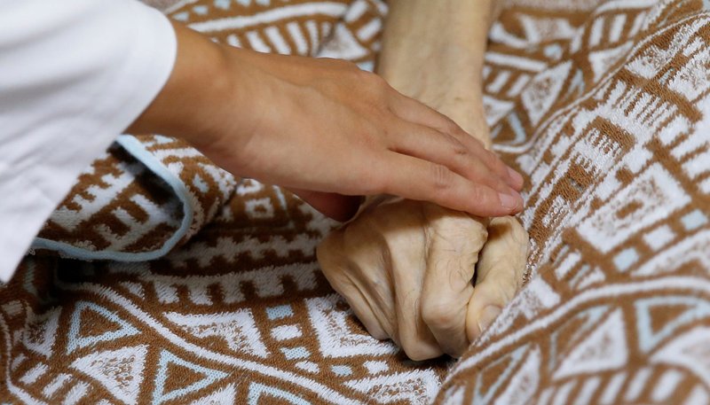 La doctora Sayaka Ogasawara, de la Clínica Yamato, toca la mano de Yasuhiro Sato mientras confirma la muerte de Sato en su casa de Tokio, en esta foto de archivo del 13 de septiembre de 2017. (CNS/Toru Hanai, Reuters)