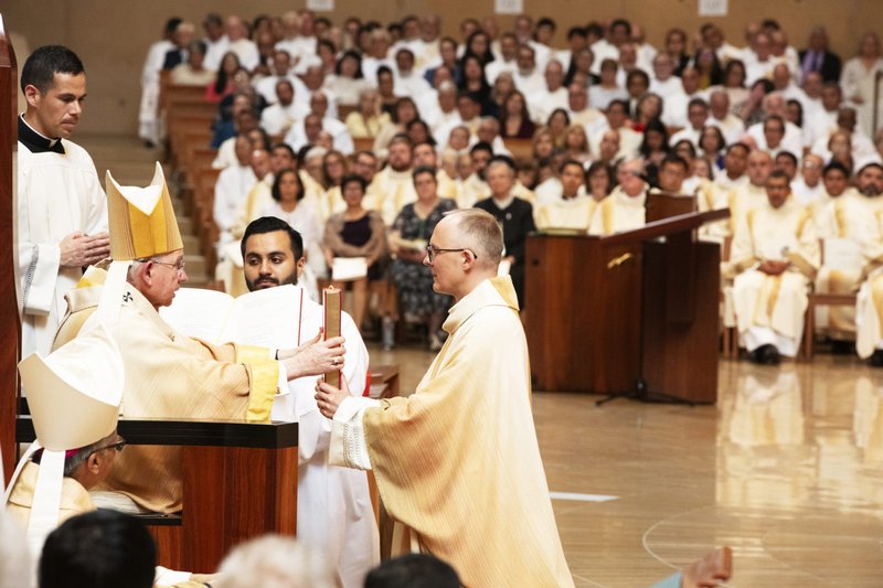 El arzobispo de Los Ángeles, José H. Gómez, entrega al obispo Slawomir Szkredka el Libro de los Evangelios durante el rito de ordenación el 26 de septiembre. (Víctor Alemán)