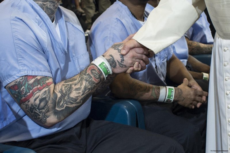 El Papa Francisco estrecha la mano de un recluso que lleva un tatuaje en el correccional Curran-Fromhold de Filadelfia el 27 de septiembre de 2015. (CNS /L'Osservatore Romano)