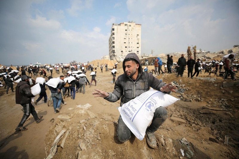 Palestinos llevan bolsas de harina que cogieron de un camión de ayuda cerca de un puesto de control israelí en la ciudad de Gaza, 19 de febrero de 2024. Los residentes de Gaza se enfrentan a niveles críticos de hambre, en medio del actual conflicto entre Israel y Hamás. (Foto de OSV News/Kosay Al Nemer, Reuters)