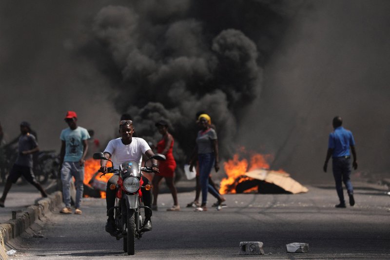 Un hombre pasa en coche junto a una barricada en llamas durante una protesta contra el gobierno del primer ministro haitiano Ariel Henry y la inseguridad en Puerto Príncipe el 1 de marzo de 2024. (Foto de OSV News/Ralph Tedy Erol, Reuters)