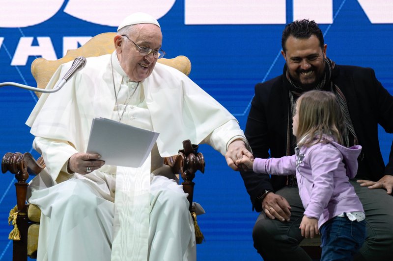 Pope Francis greets a child during a meeting on Italy's declining birthrate at an auditorium in Rome May 10, 2024. To the pope's left is Gianluigi De Palo, president of the Foundation for Natality, which organizes the annual meeting. (CNS photo/Vatican Media)